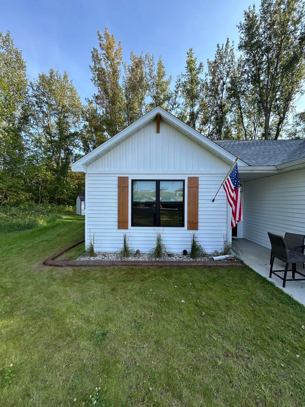 White house exterior with American flag, wooden shutters, and landscaped yard.